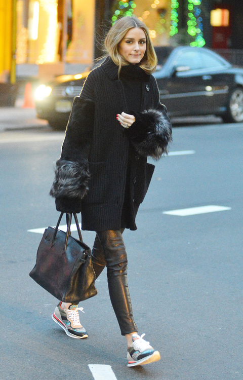 Olivia Palermo stops to stand on a chair and pose for a photo while out with her husband in NYC