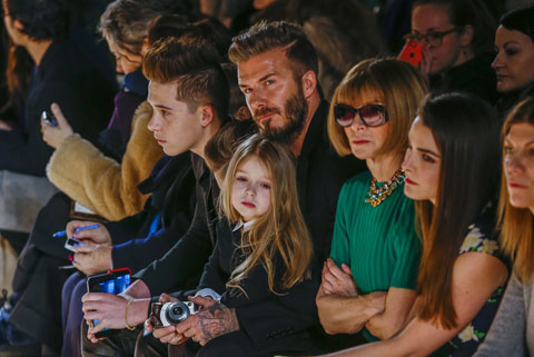British former soccer player David Beckham sits next to U.S. Vogue editor Anna Wintour (3rd R) with his daughter, Harper, on his lap during a presentation of the Victoria Beckham Fall/Winter 2015 collection during New York Fashion Week
